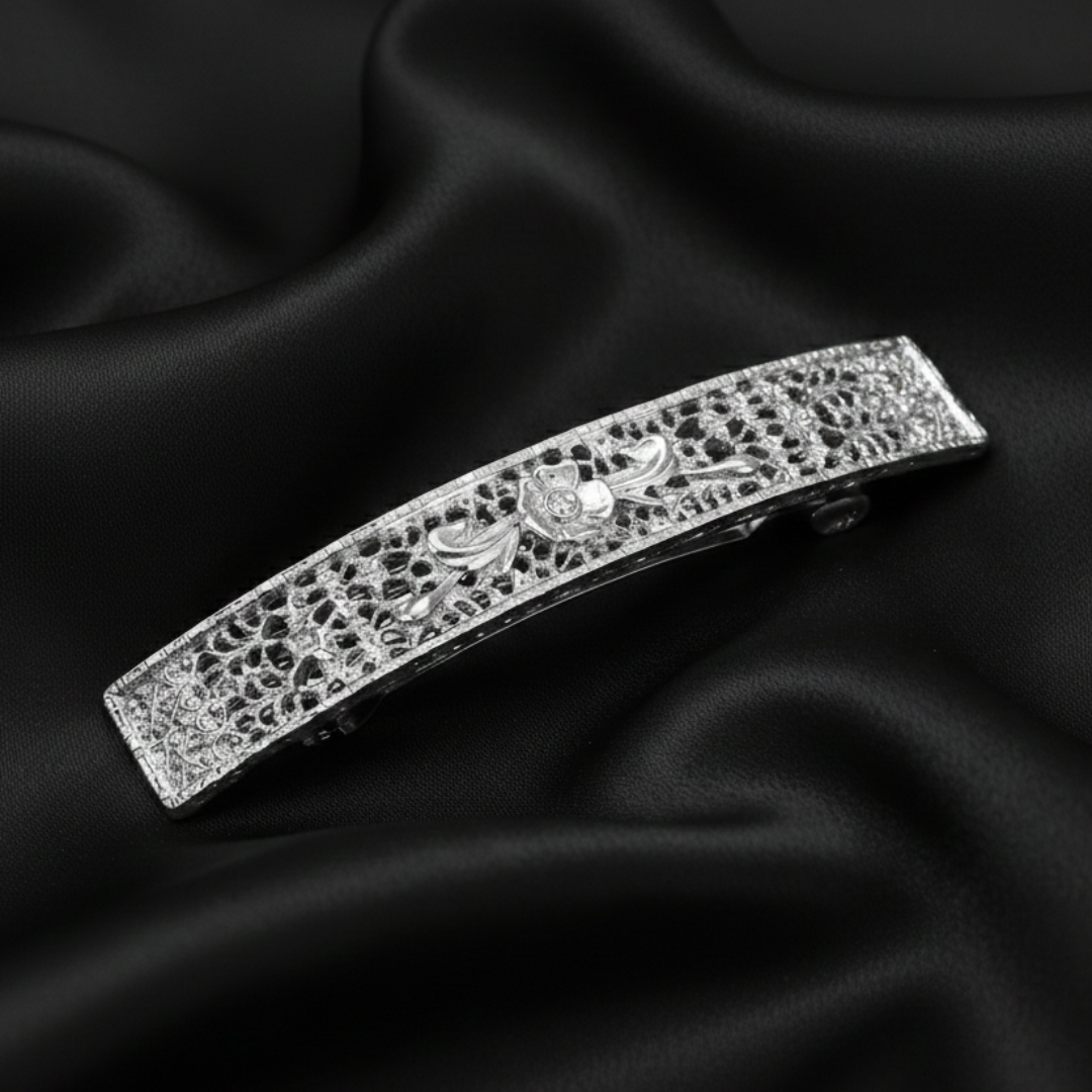 Silver tone floral barrette on a black fabric background.