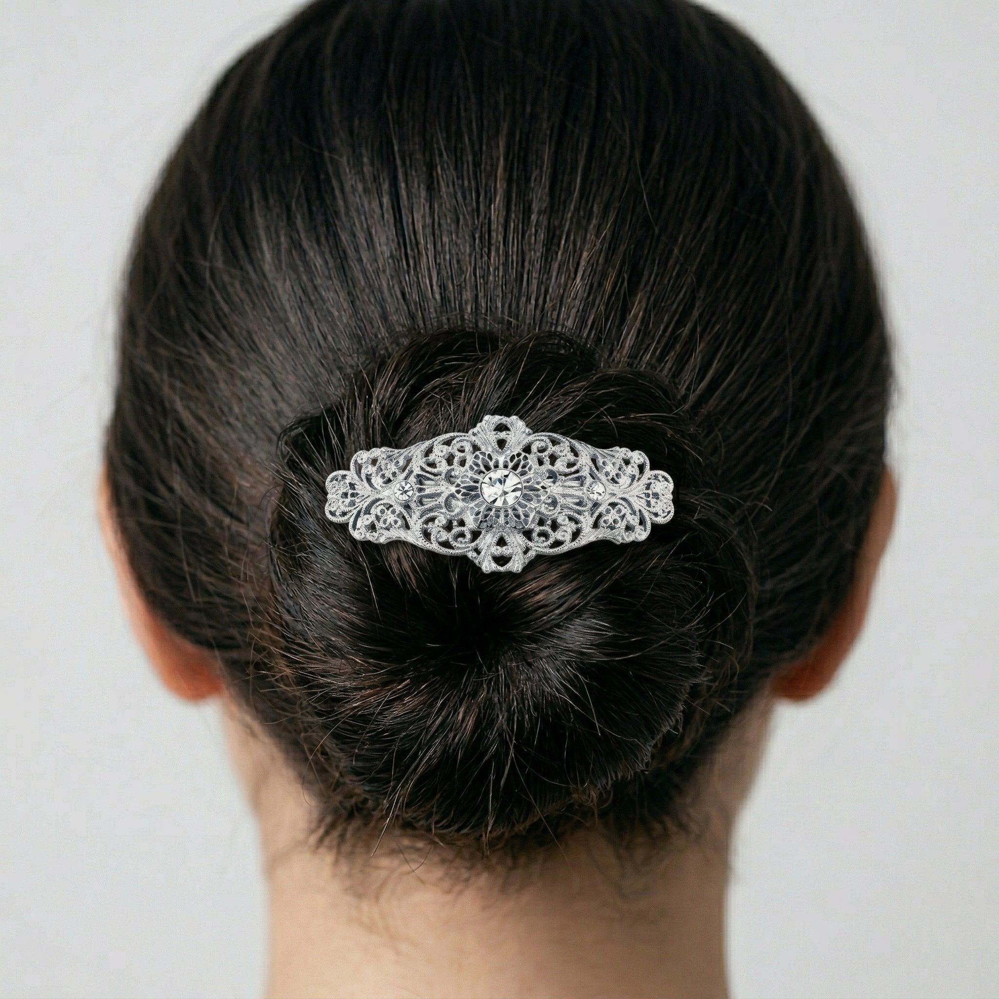 Opulent Filigree Round Crystal Bar Hair Barrette in a woman's hair bun on a plain background