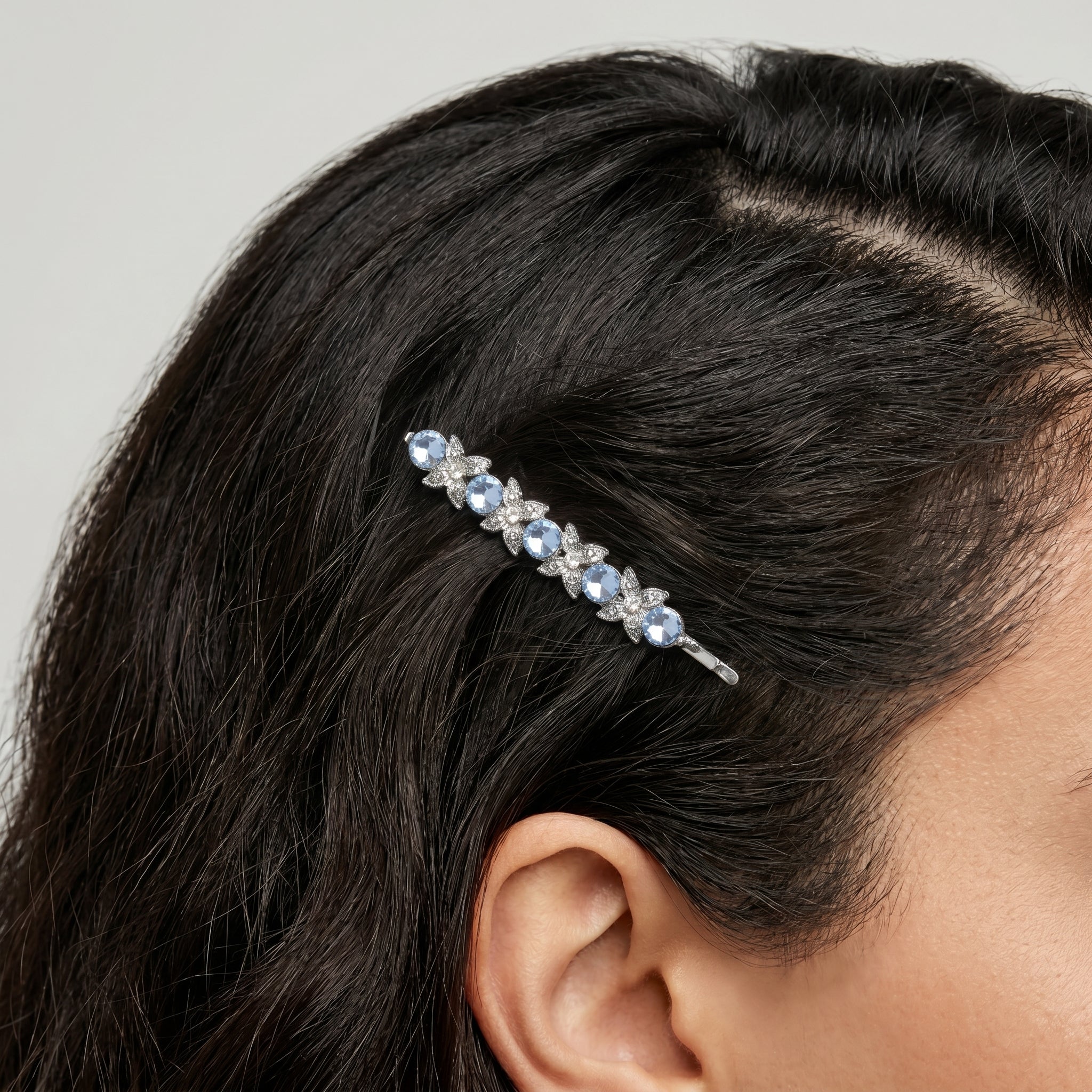 Woman wearing a blue crystal bobby pin hair clip with a floral design