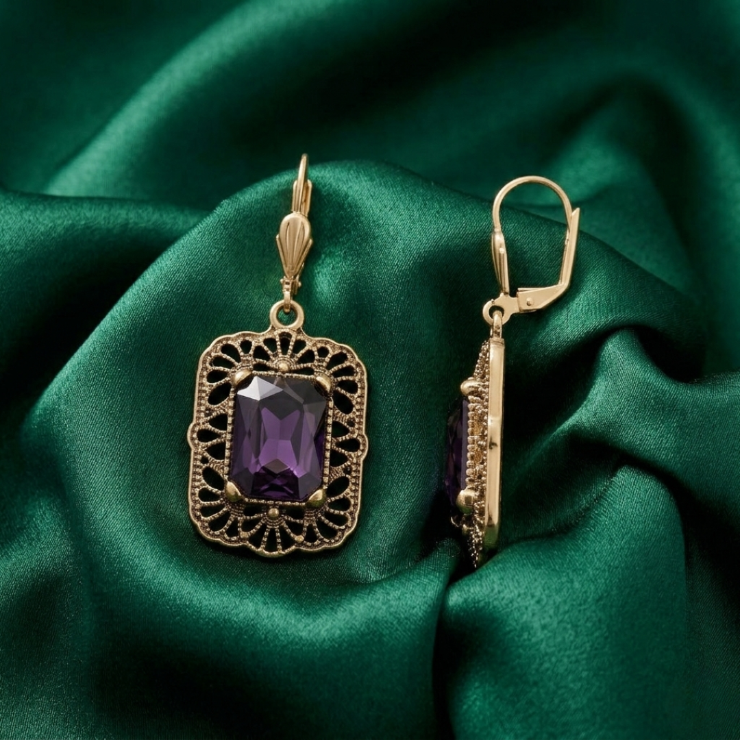 Gold earrings with purple crystals on green satin fabric