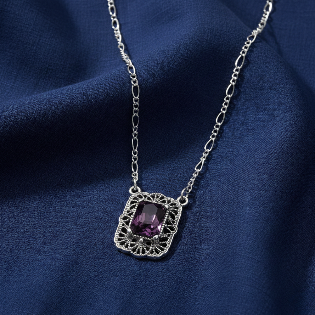 Silver necklace with a purple crystal pendant on a blue fabric background