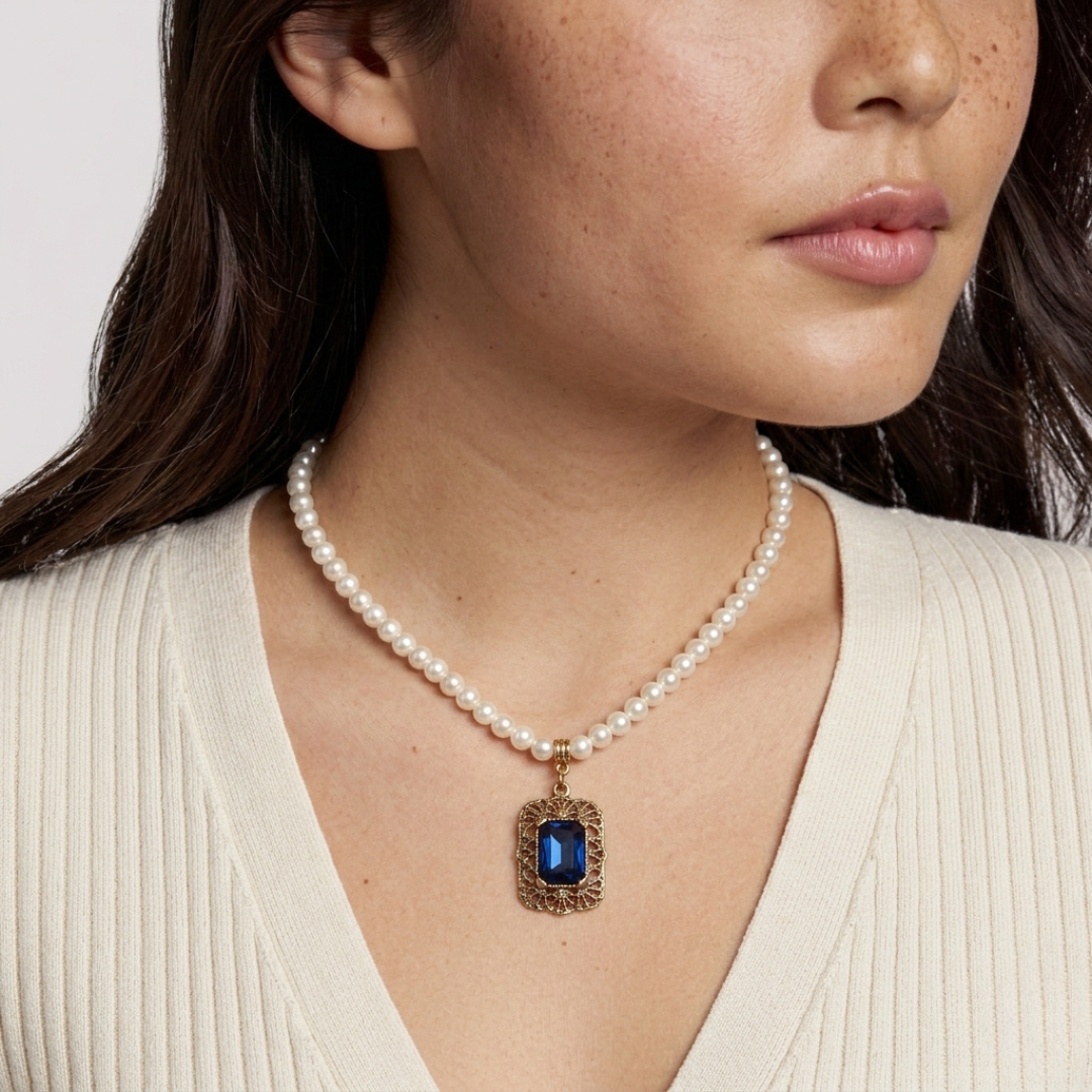 Faux pearl necklace with a blue crystal pendant worn by a person
