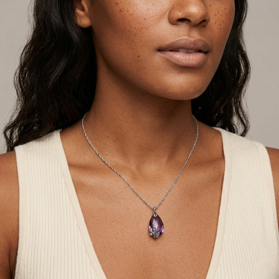 Woman wearing a necklace with a purple crystal pendant against a neutral background