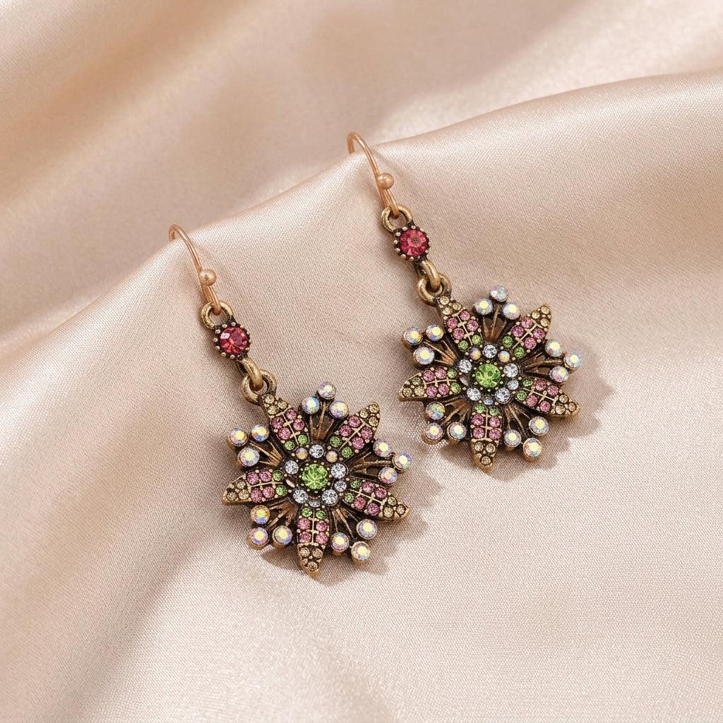Multicolored crystal earrings designed in the shape of a flower that rests on a cream satin fabric surface