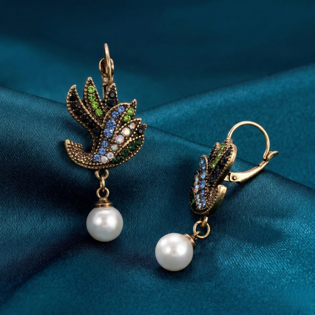 Ornate earrings with faux pearl drops on a teal fabric background