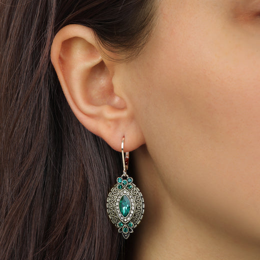 Close up of a woman wearing Emerald Green Navette & Clustered Crystal Drop Earrings