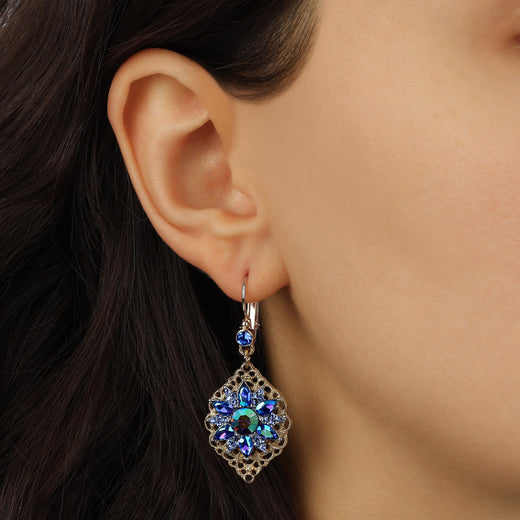 Close up of a woman wearing Antiqued Filigree Iridescent Blue AB Crystal & Sapphire Blue Stone Flower Drop Earrings
