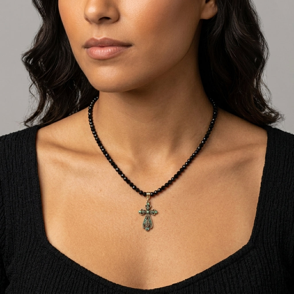 Black beaded necklace with a cross pendant worn by a person against a neutral background