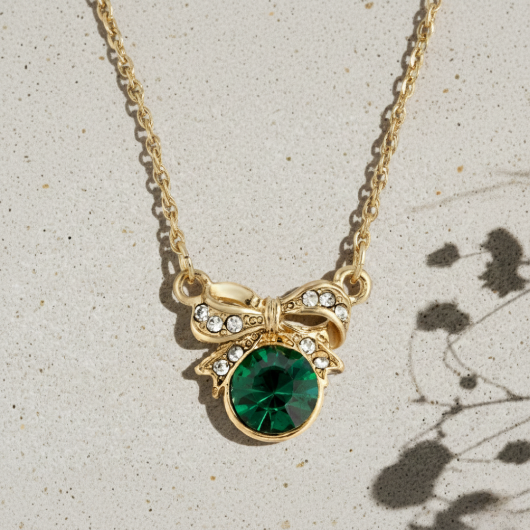 Gold necklace with a green gemstone pendant on a light gray background.
