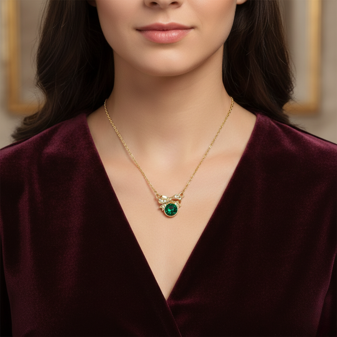 Woman wearing a gold necklace with a green gemstone pendant.