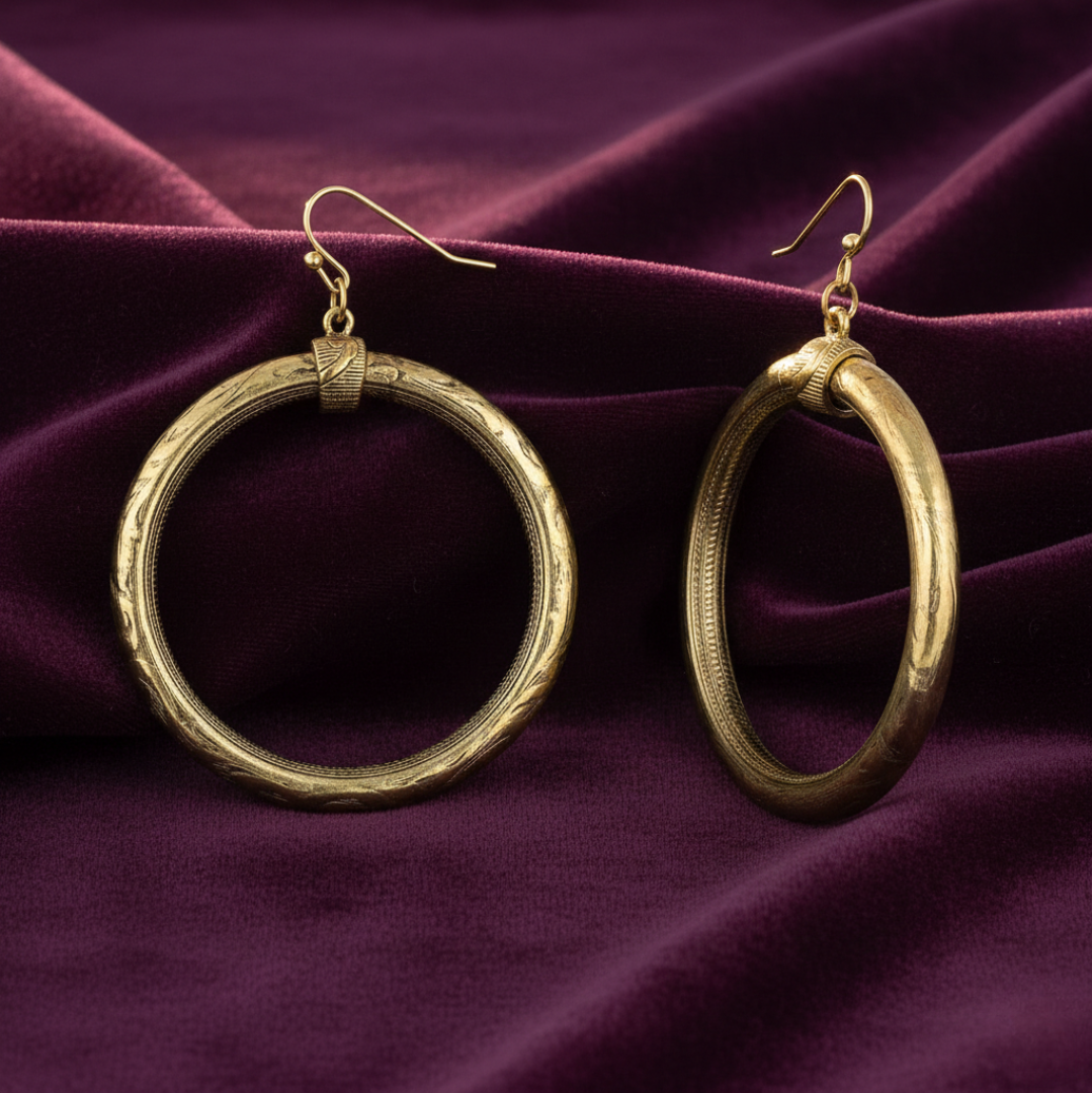 Gold hoop earrings on a purple fabric background