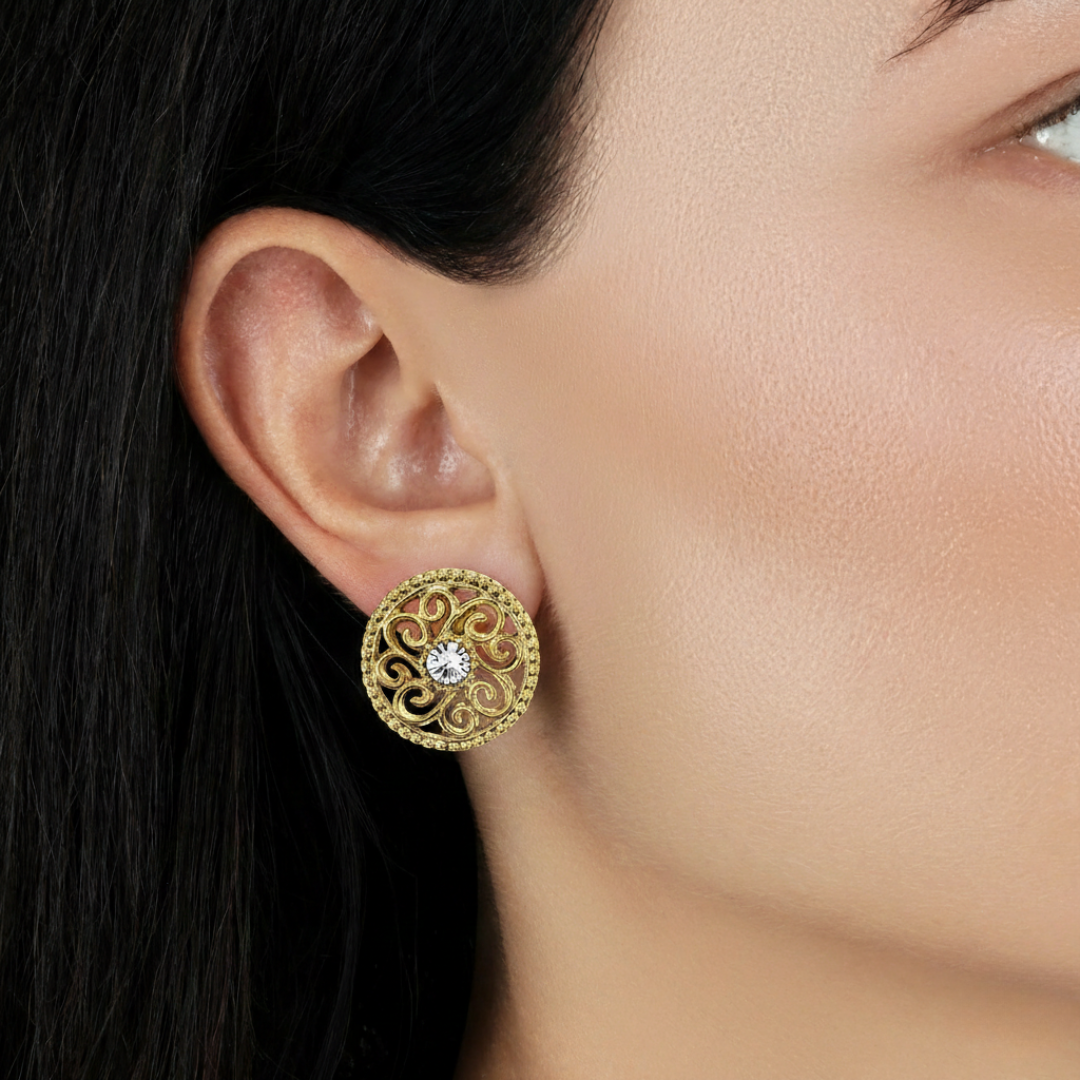 Gold earring with a clear crystal on an ear, close-up view.