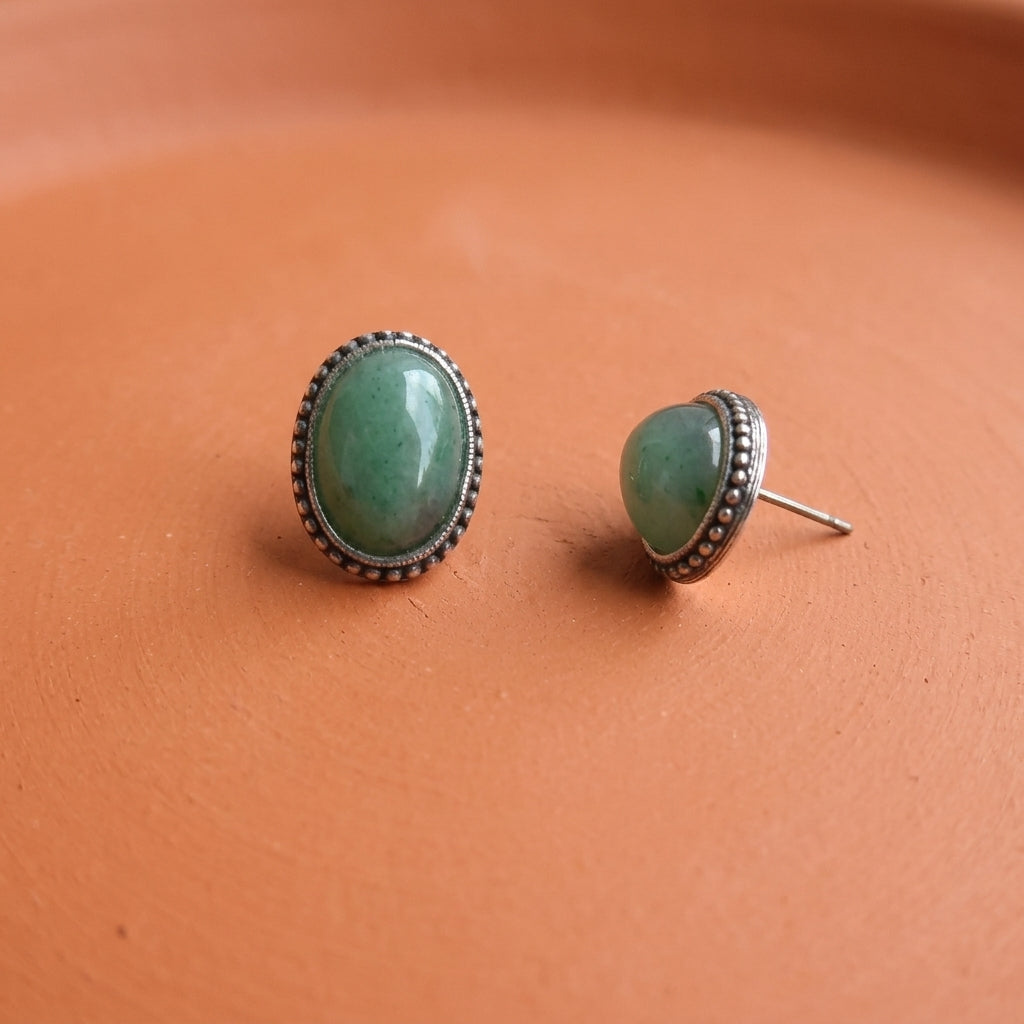 Antiqued Green Aventurine Gemstone Post Earrings resting on smooth red clay