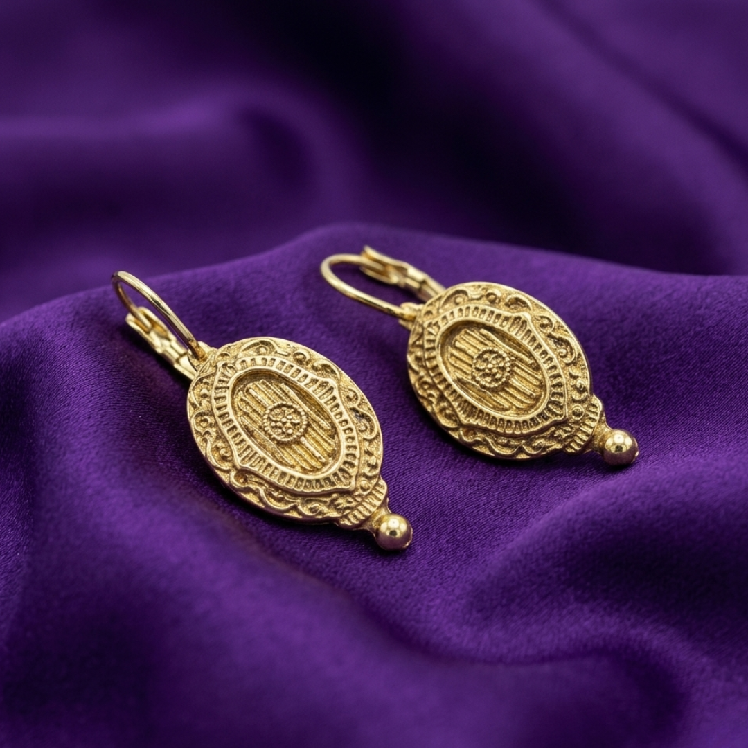 Gold tone Baroque Insignia Oval Drop Earrings on purple satin fabric