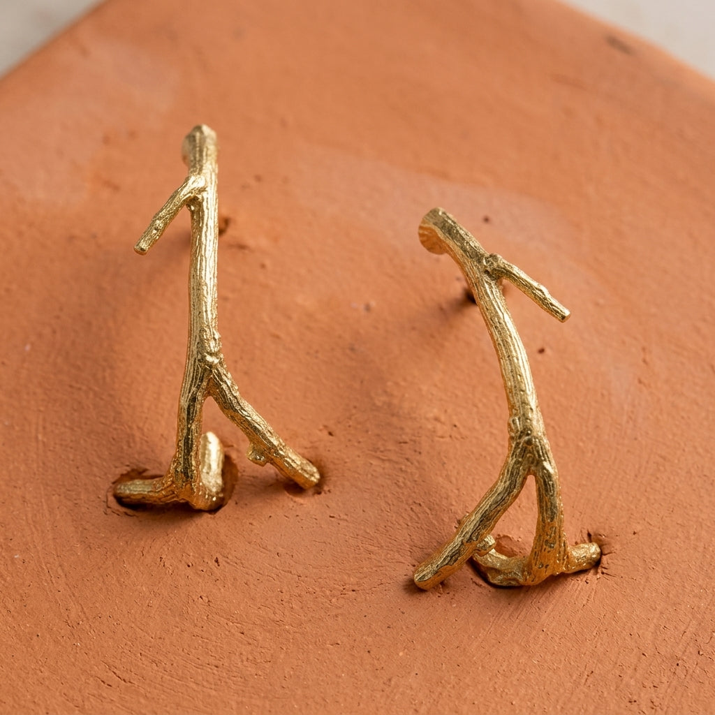Small Tree Branch Hoop Earrings displayed on a textured terracotta surface.