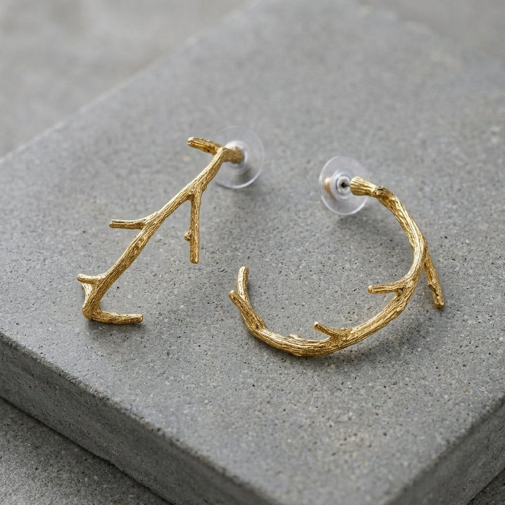 Large Tree Branch Hoop Earrings displayed on a gray stone surface.