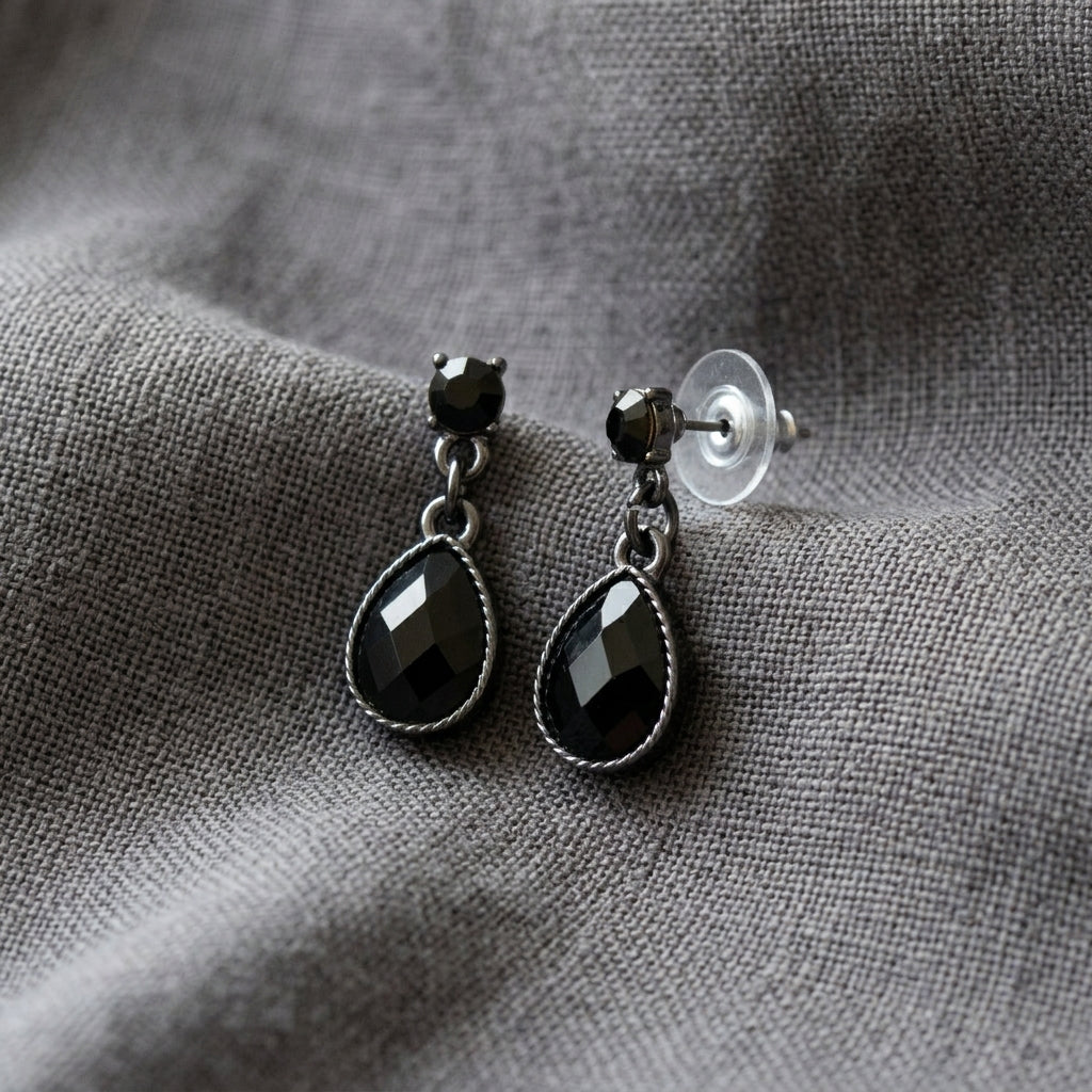 Petite Jet Black Stone Teardrop Post Dangle Earrings resting on gray linen fabric