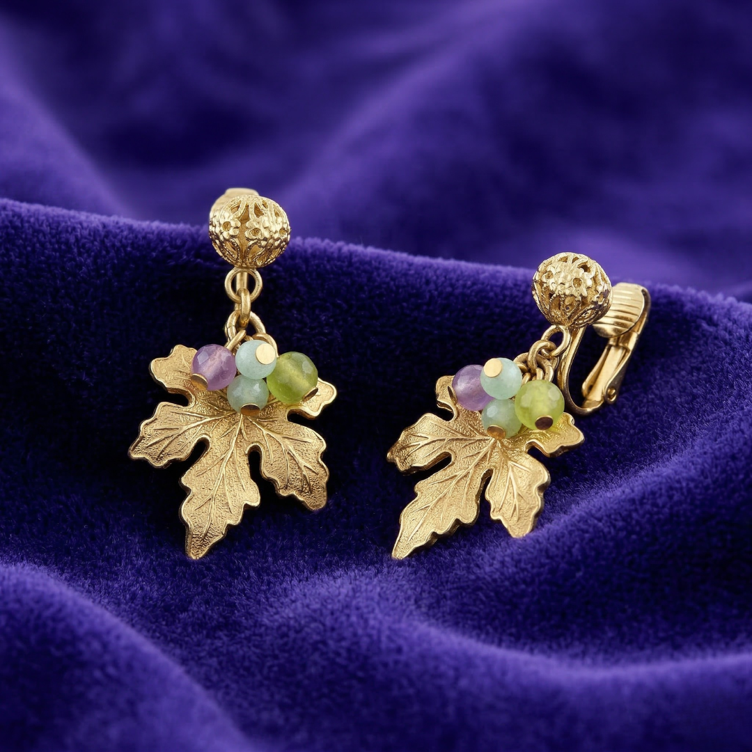 Gold-dipped leaf and grap earrings with multicolor beads on a purple fabric background
