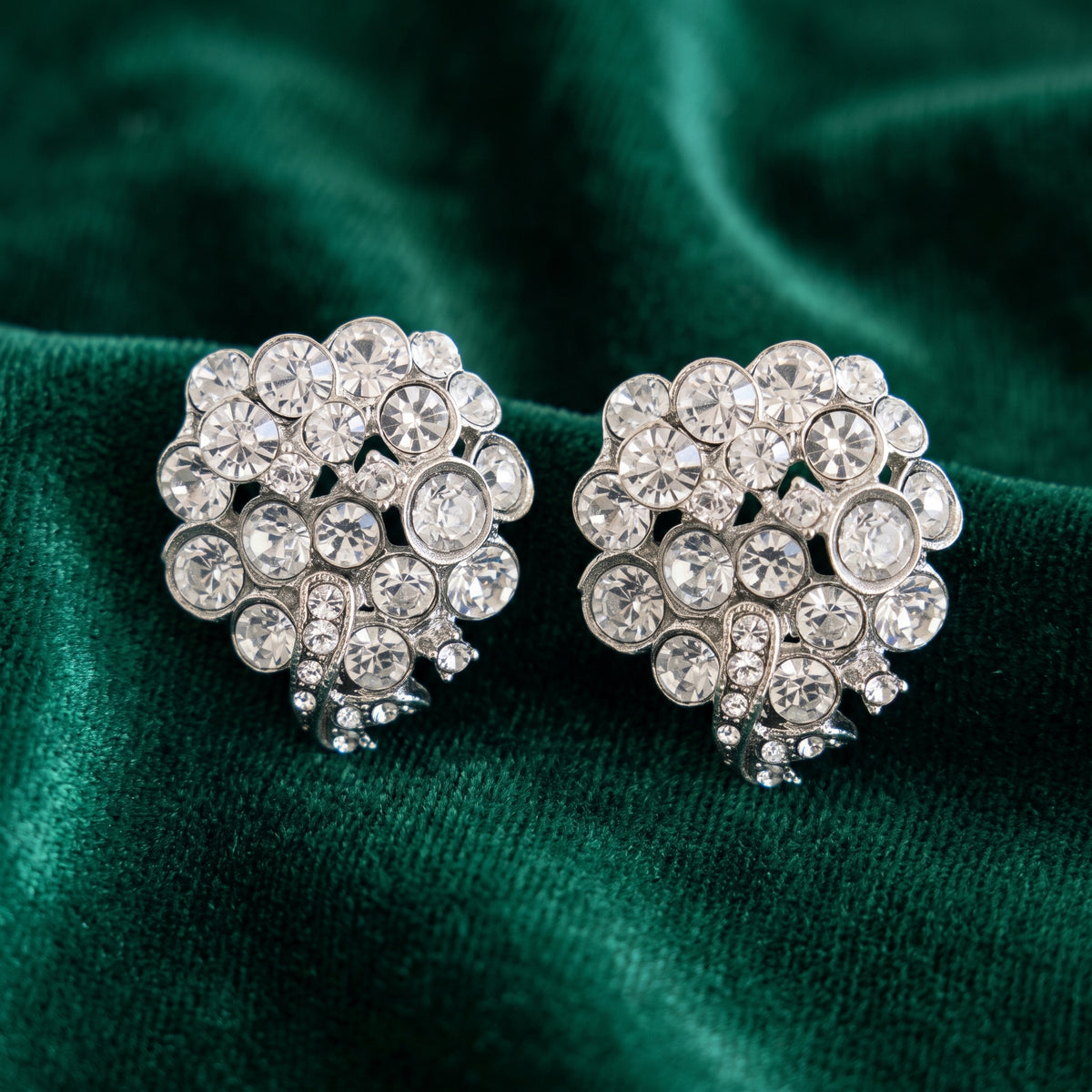 Antiquities Couture Bridal Austrian Crystal Cluster Post Stud Earrings, displayed on a draped dark green velvet fabric.