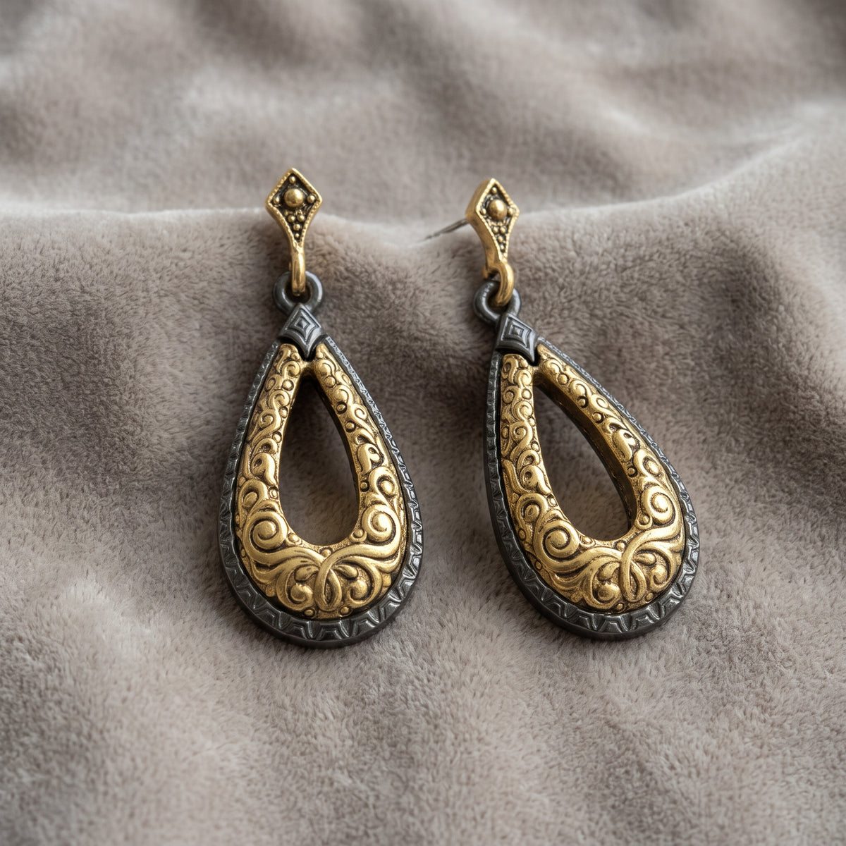 Antiquities Couture Two Tone Teardrop Earrings displayed on a textured greige fabric background.