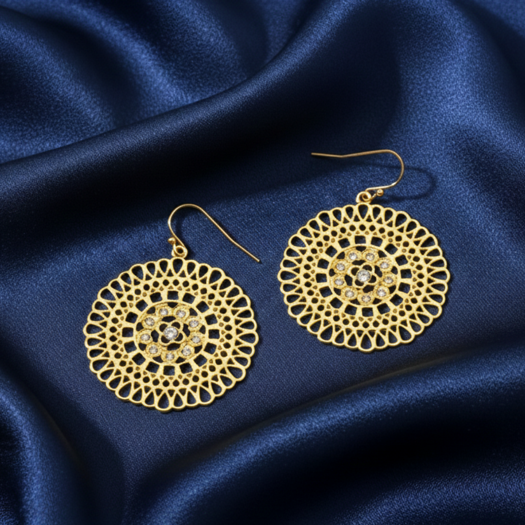 Gold earrings with intricate designs on a blue satin background