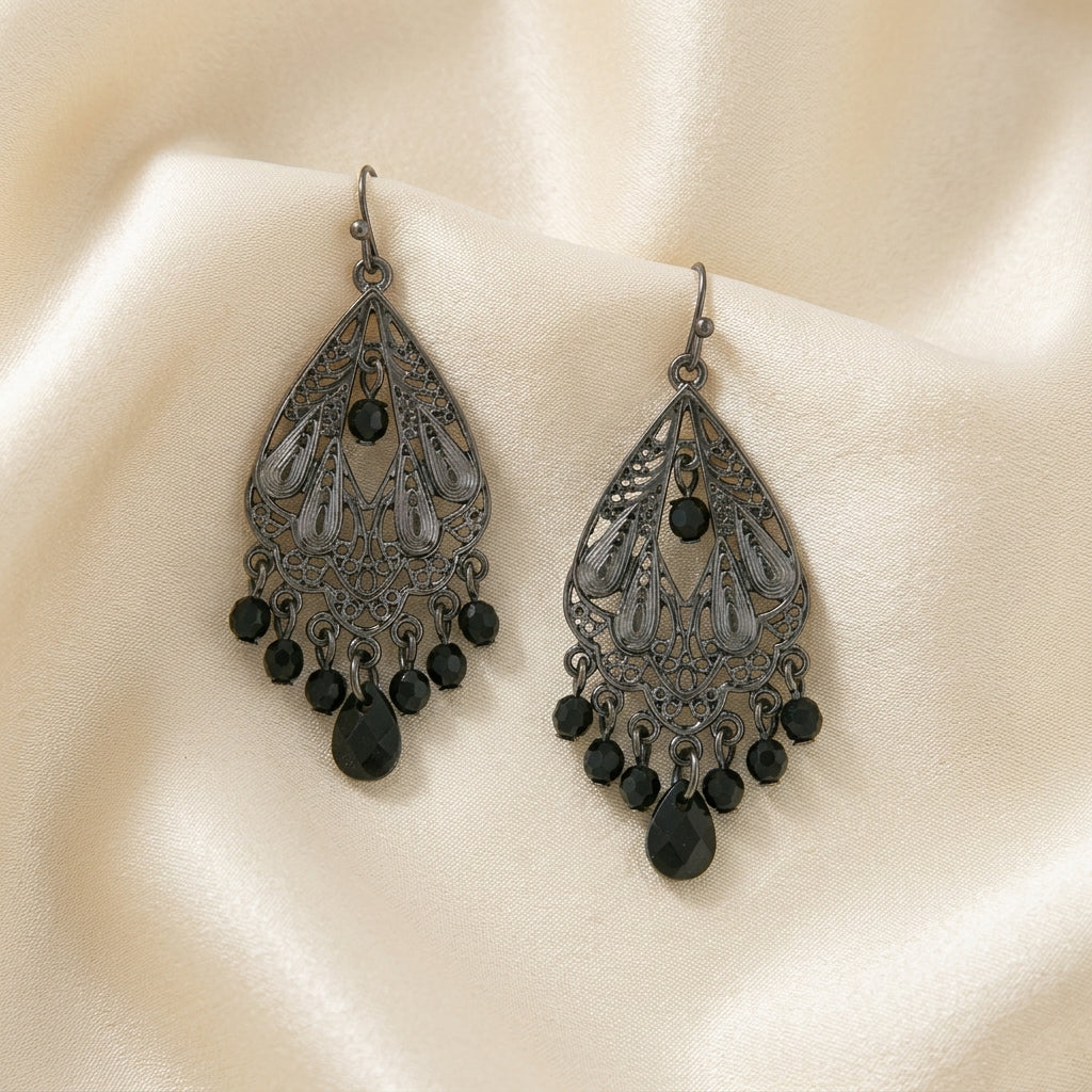 Black Faceted Bead Filigree Chandelier Earrings resting on cream colored silk