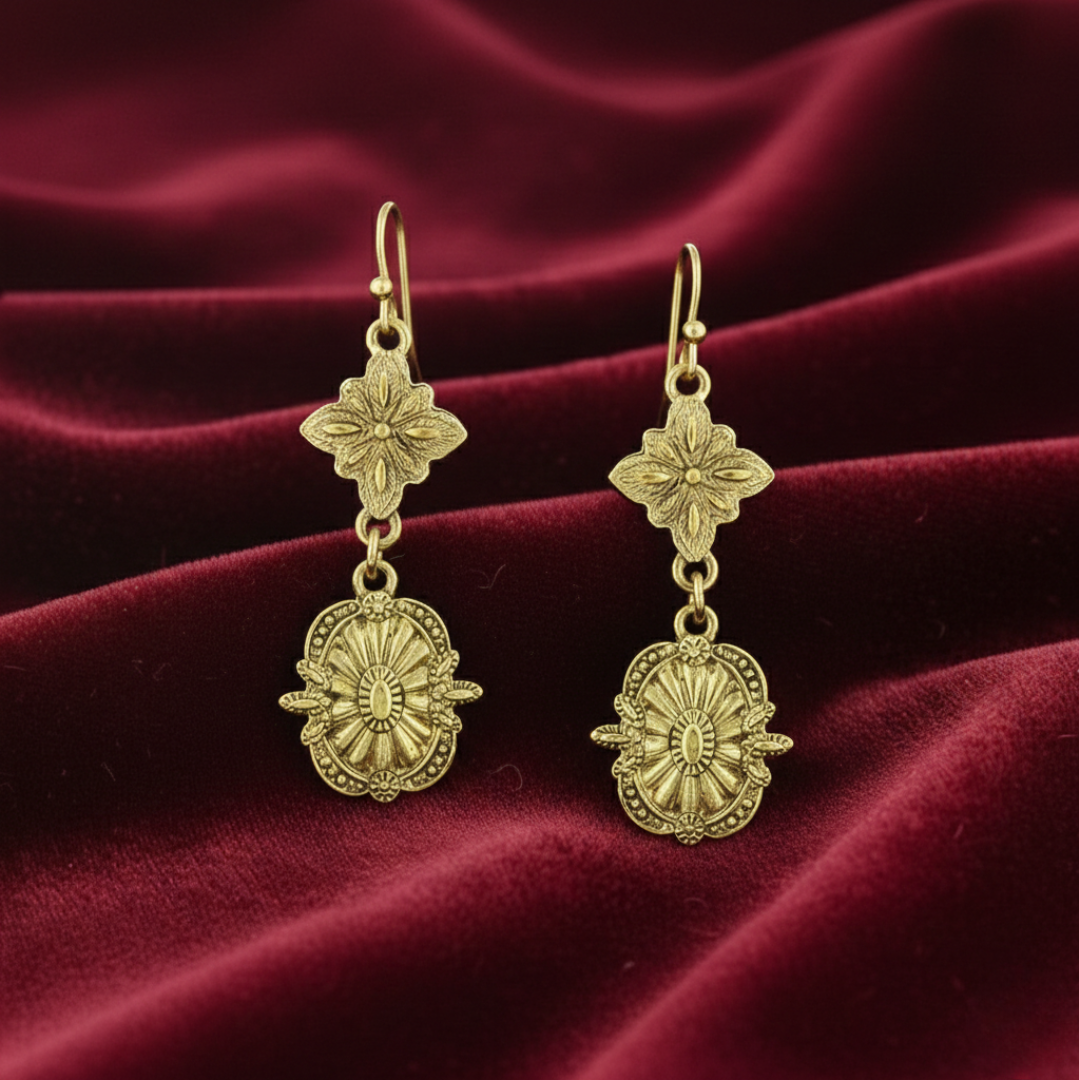 Gold earrings with floral designs on a red velvet background.