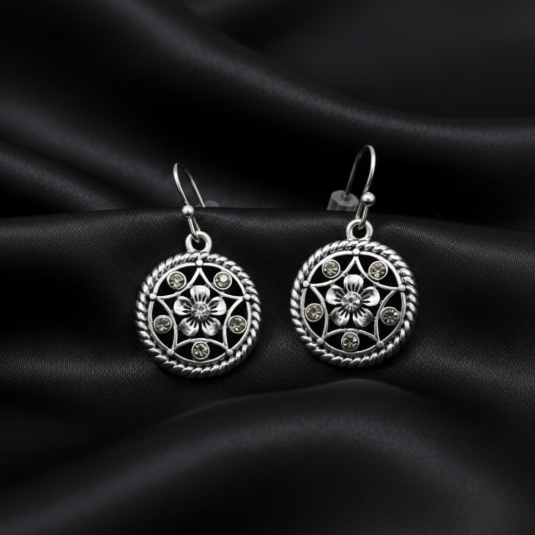 Silver floral earrings on black satin fabric
