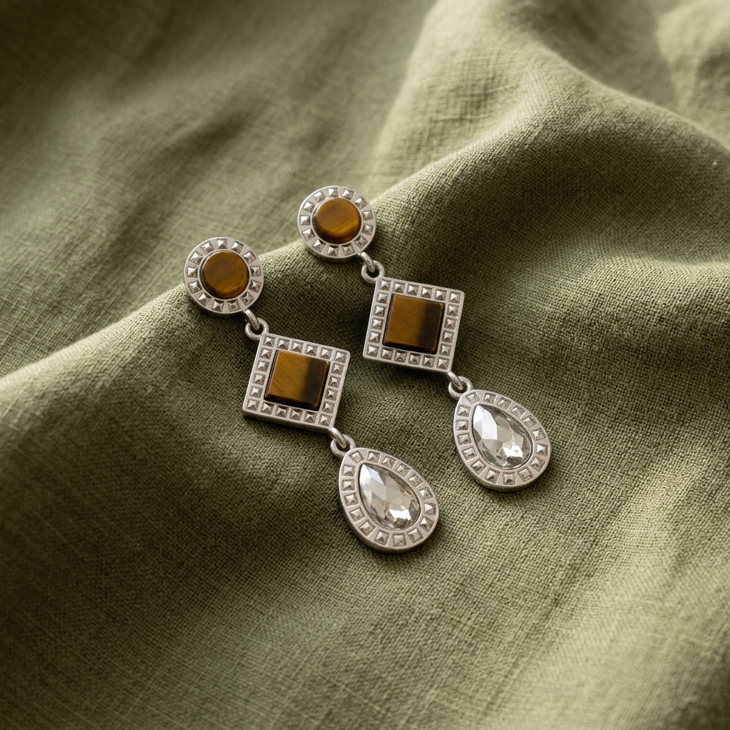 Round Square Tigers Eye Gemstone Teardrop Earrings resting on dark green fabric