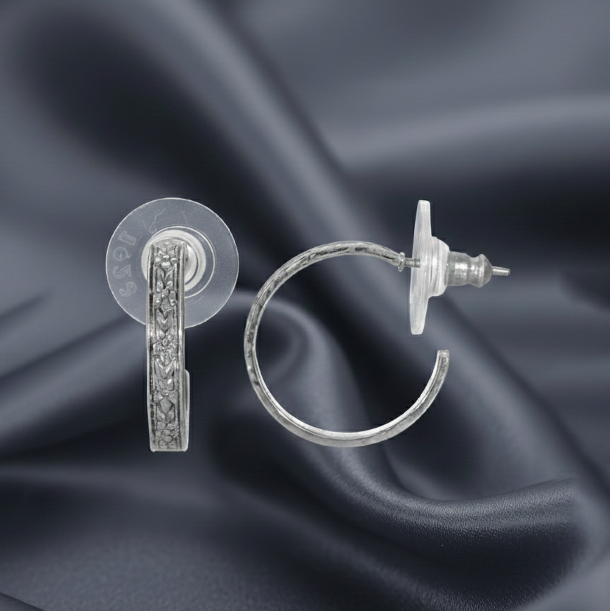 Silver hoop earrings on a charcoal-colored fabric background.