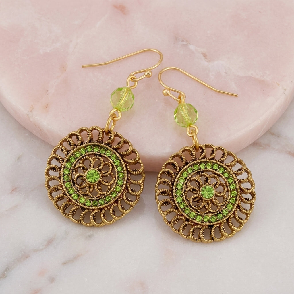 Round Filigree Multi Light Green Crystal Dangle Earrings resting on marble