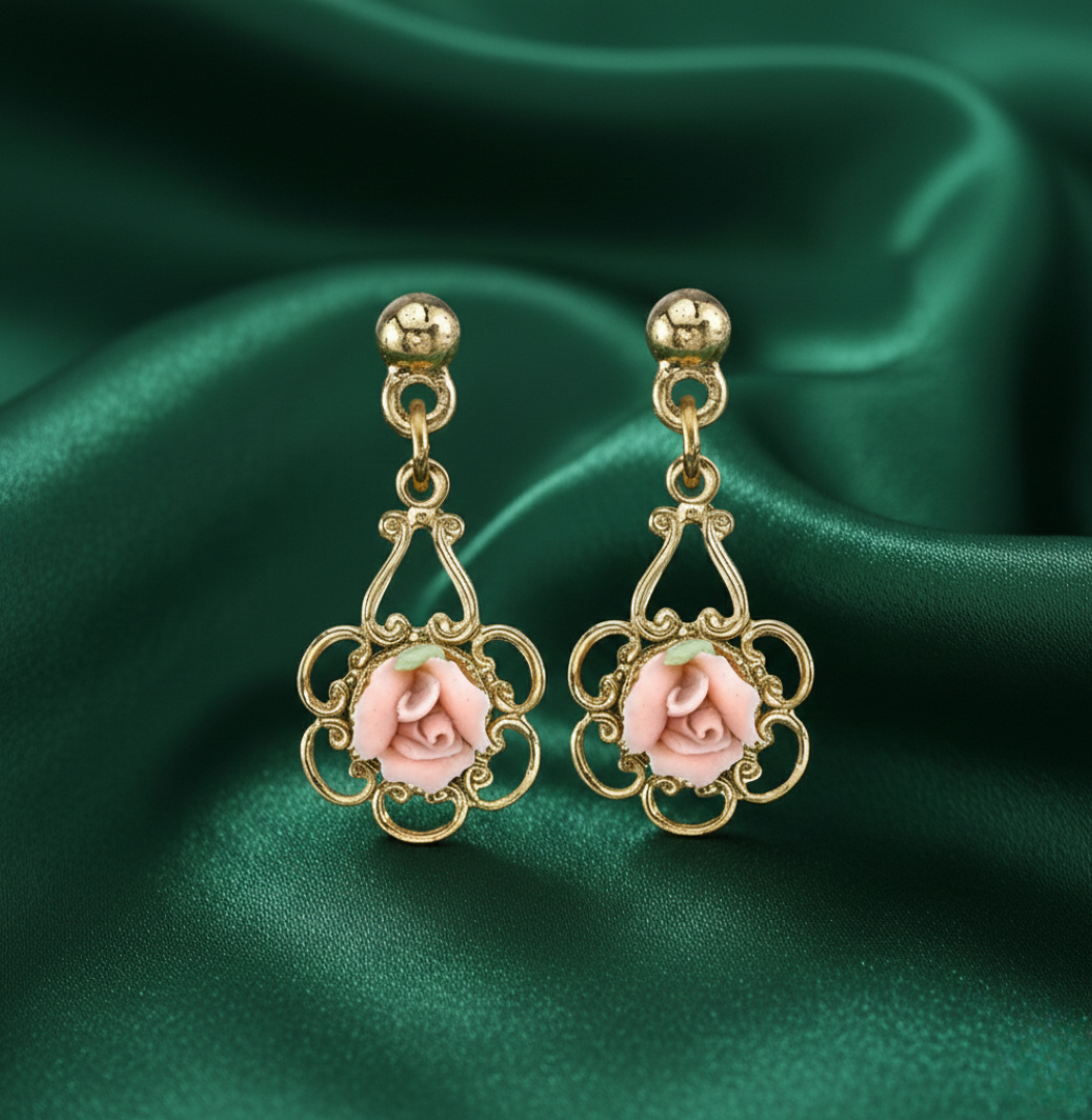 Gold earrings with porcelain rose design on a green satin background