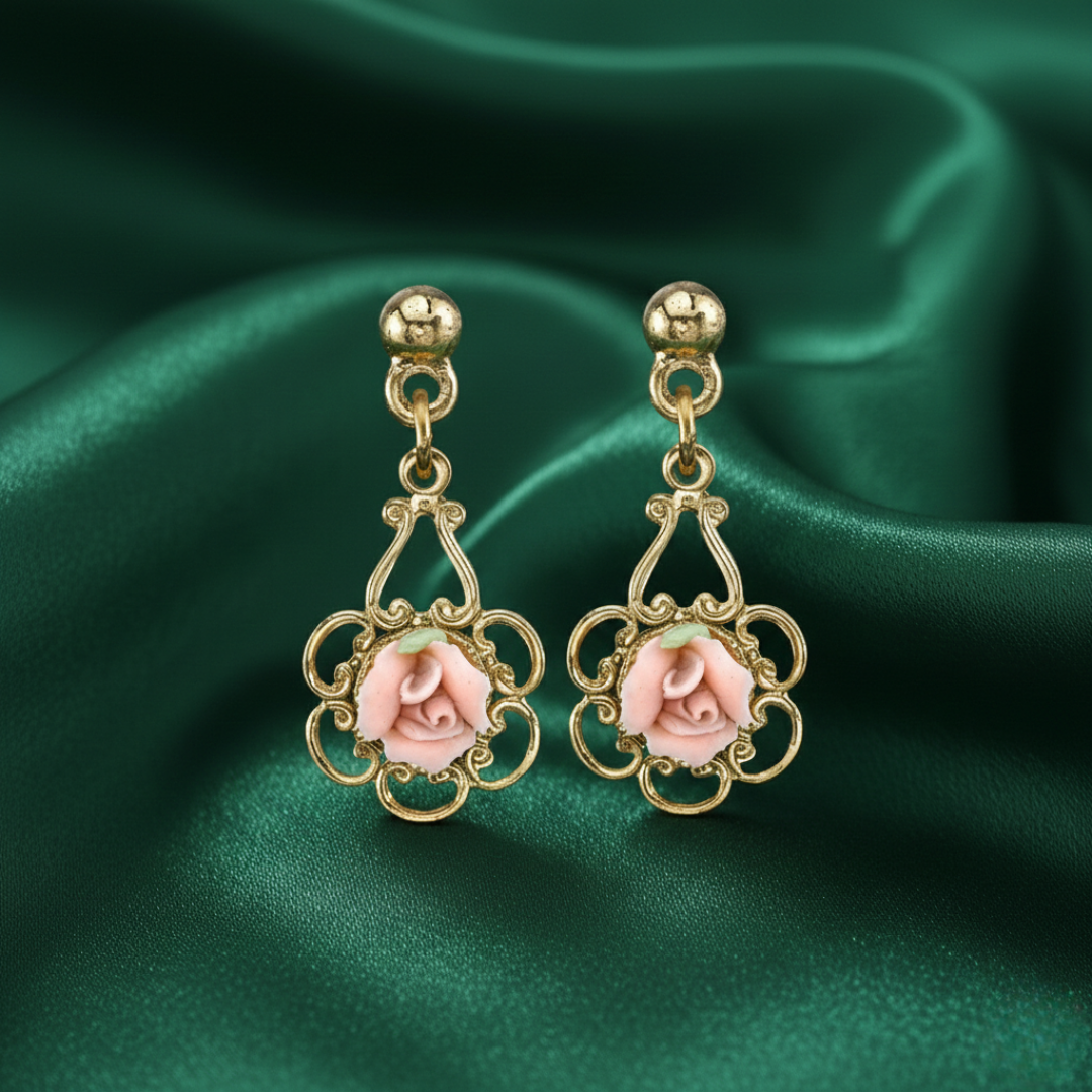 Gold earrings with porcelain rose design on a green satin background