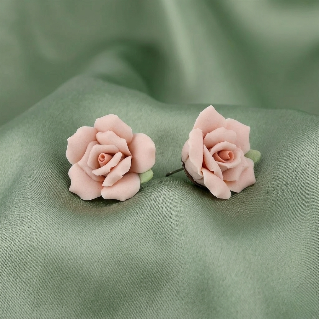 Pink rose-shaped earrings on a green fabric background