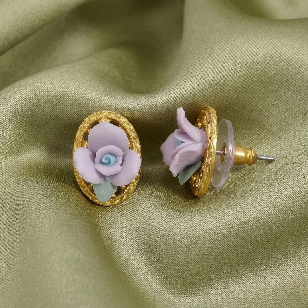 Pair of floral porcelain rose earrings with gold and purple details on a green fabric background