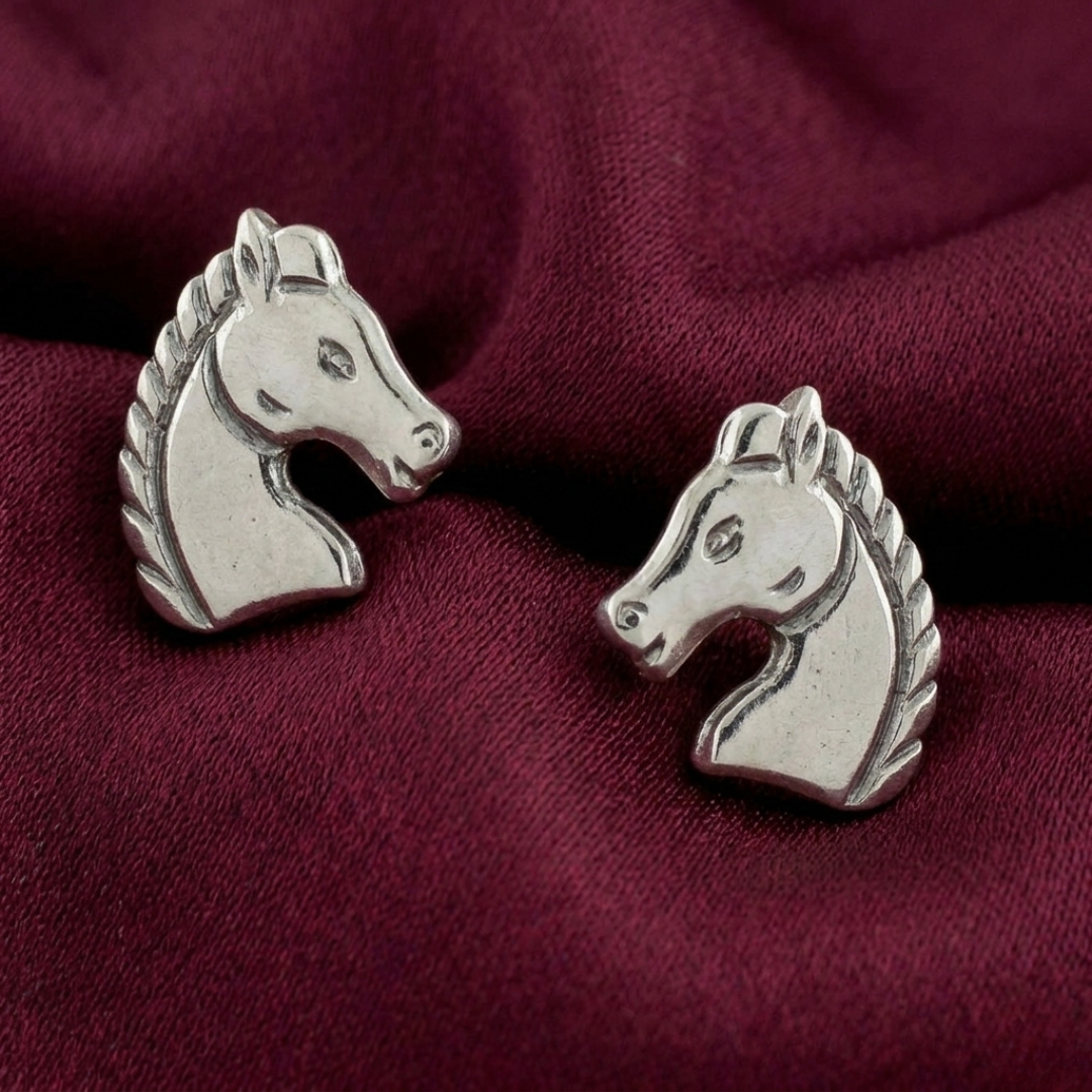 Silver horse head earrings on a burgundy fabric background
