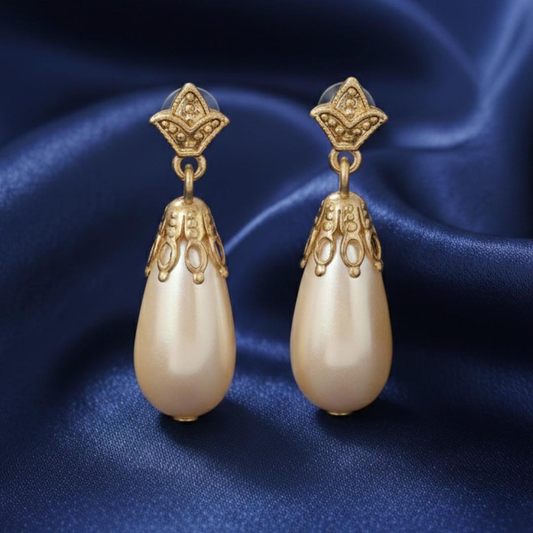 Gold earrings with pearl drops on a blue satin background