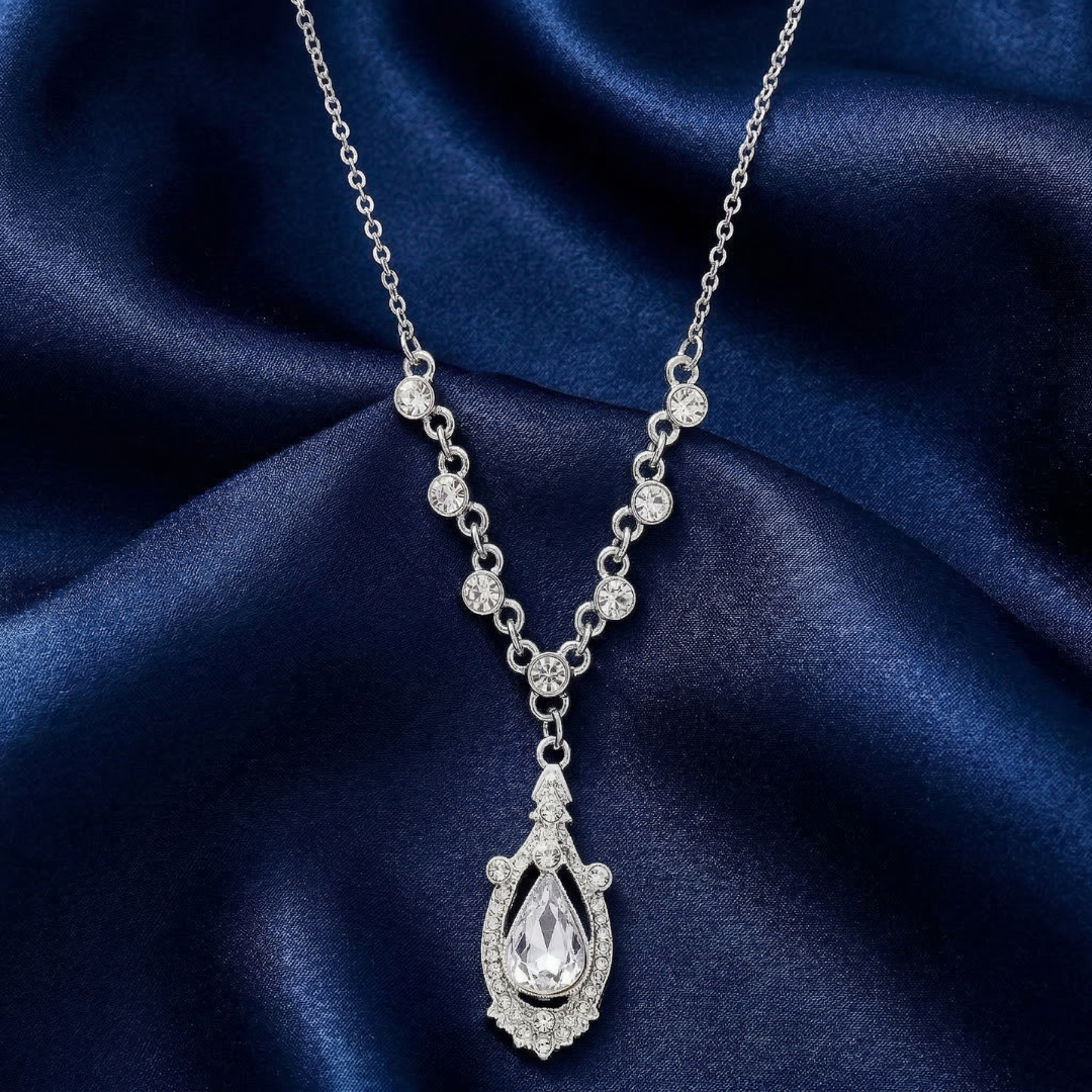 Silver and crystal necklace with a teardrop pendant on a blue satin background