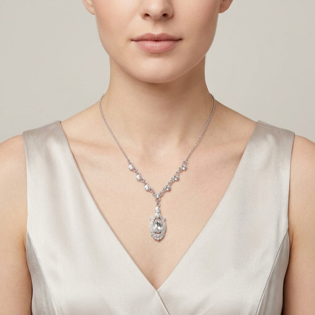 Woman wearing a silver necklace with a large crystal pendant against a neutral background