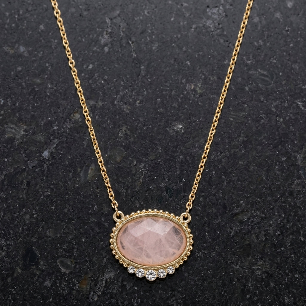 Pink Moonstone Crystal Accent Pendant Necklace resting on dark stone surface