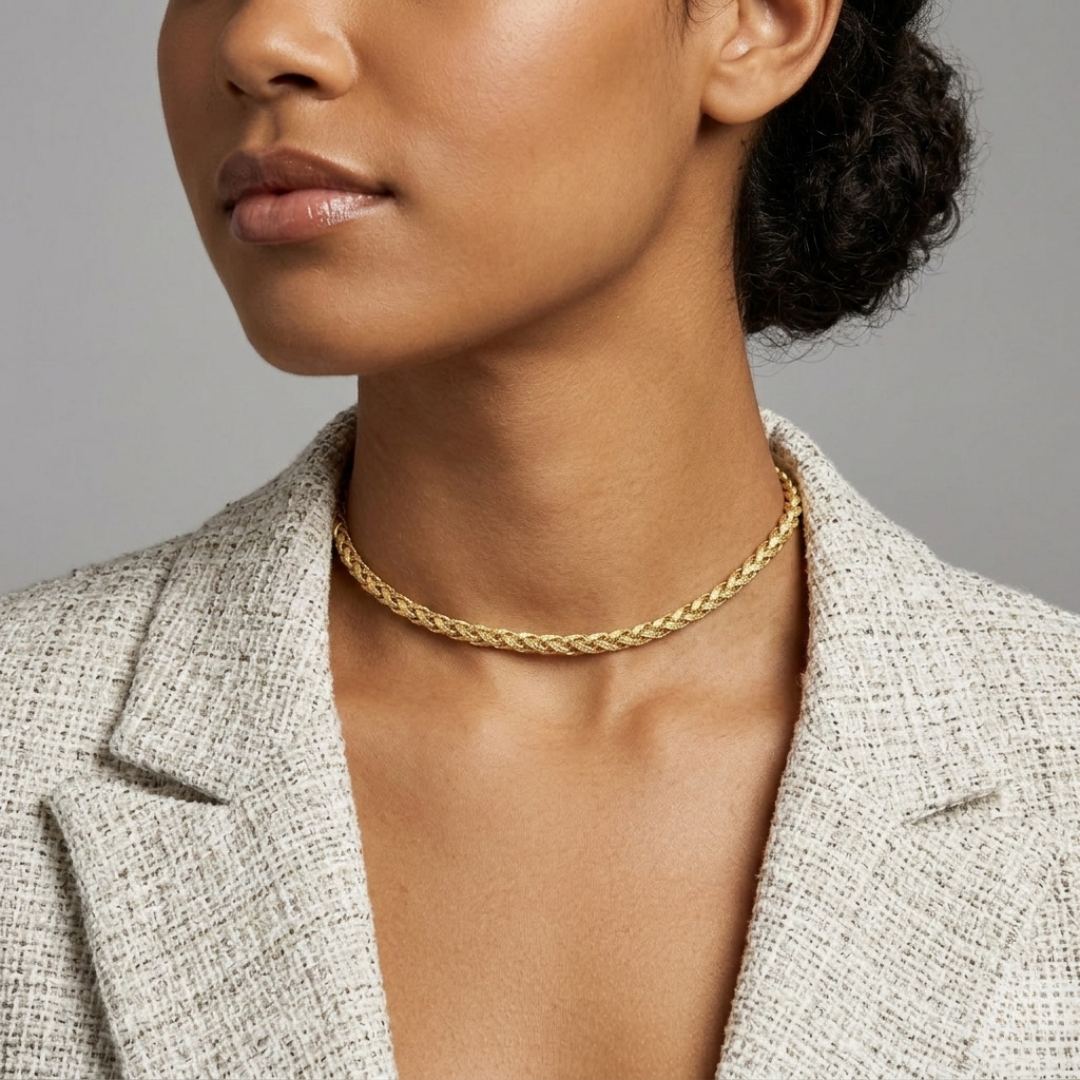 Woman wearing a gold choker necklace with a neutral background