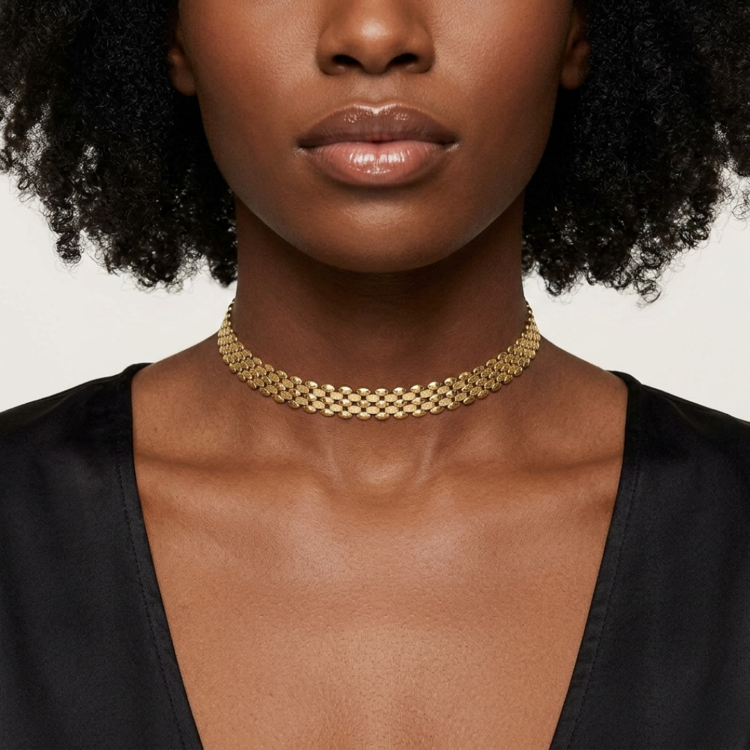 Woman wearing a gold choker necklace against a neutral background