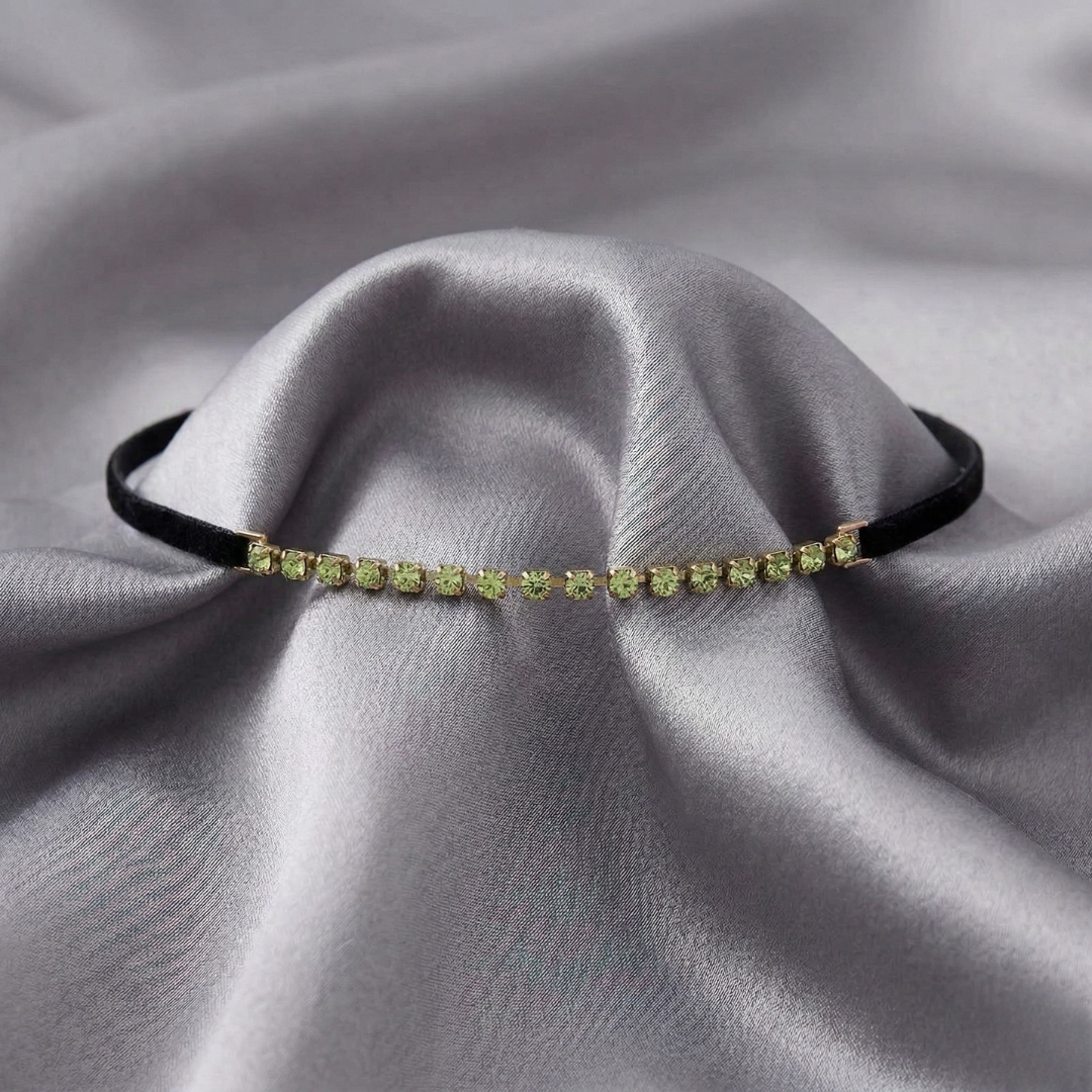 Green crystal choker necklace on a black velvet cord on gray fabric