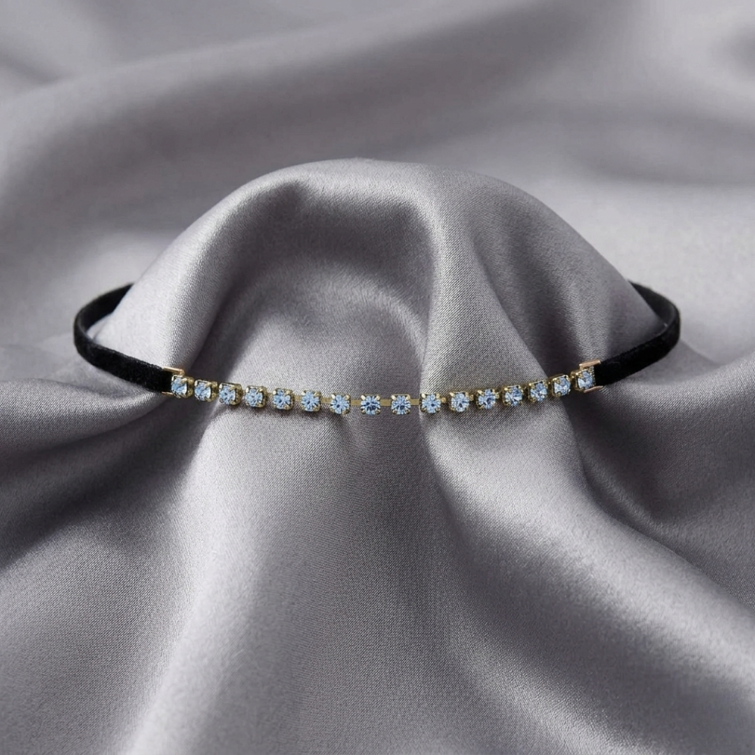 Delicate choker necklace with small blue crystals on a gray fabric background