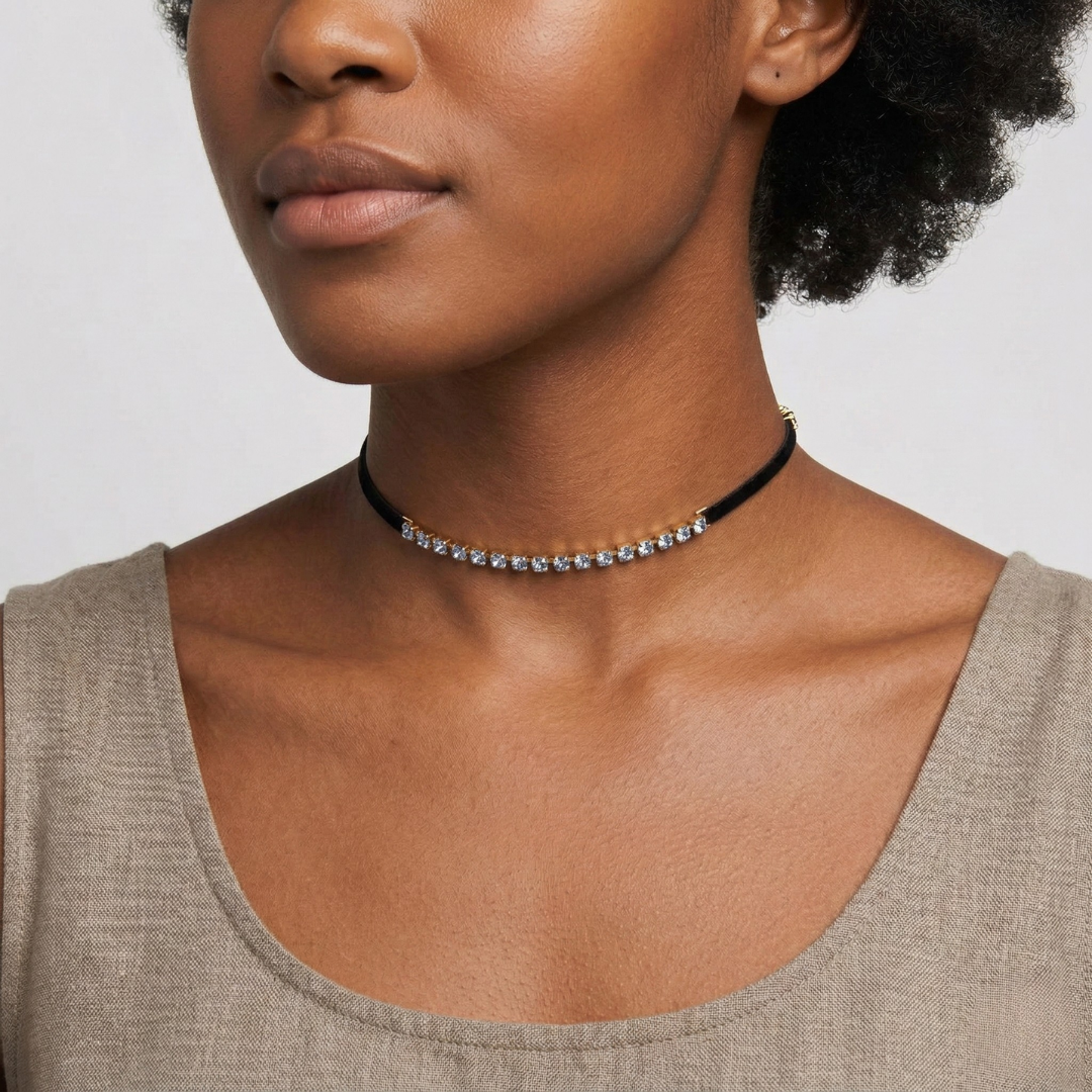 Close-up of a woman wearing a black choker necklace with small blue crystals on a plain background