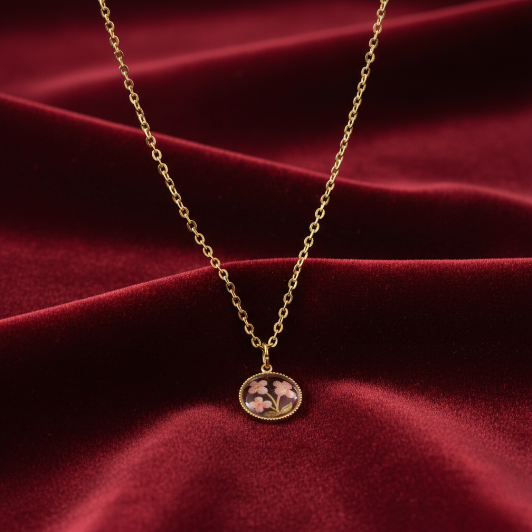 Gold necklace with a floral pendant on a red fabric background