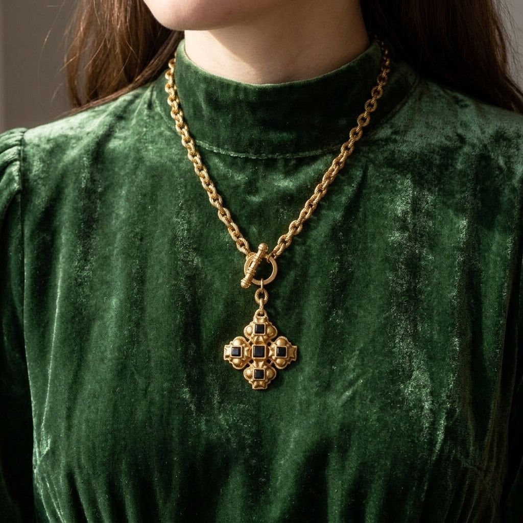 Woman in a vintage-style velvet green dress wearing a gold tone toggle chain black onyx cross pendant necklace