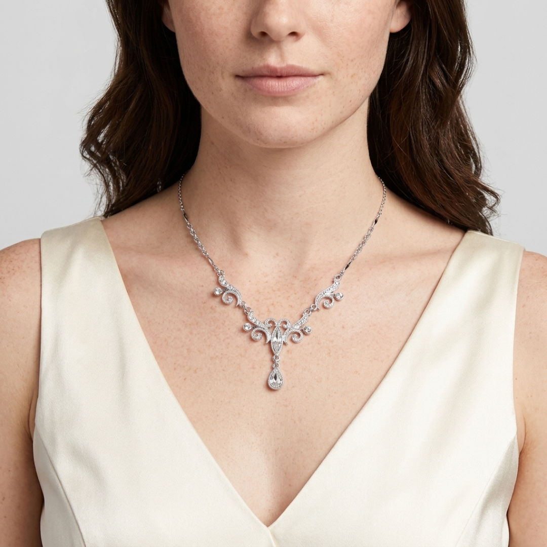 Silver tone crystal teardrop necklace worn by a model in a white dress against a neutral background
