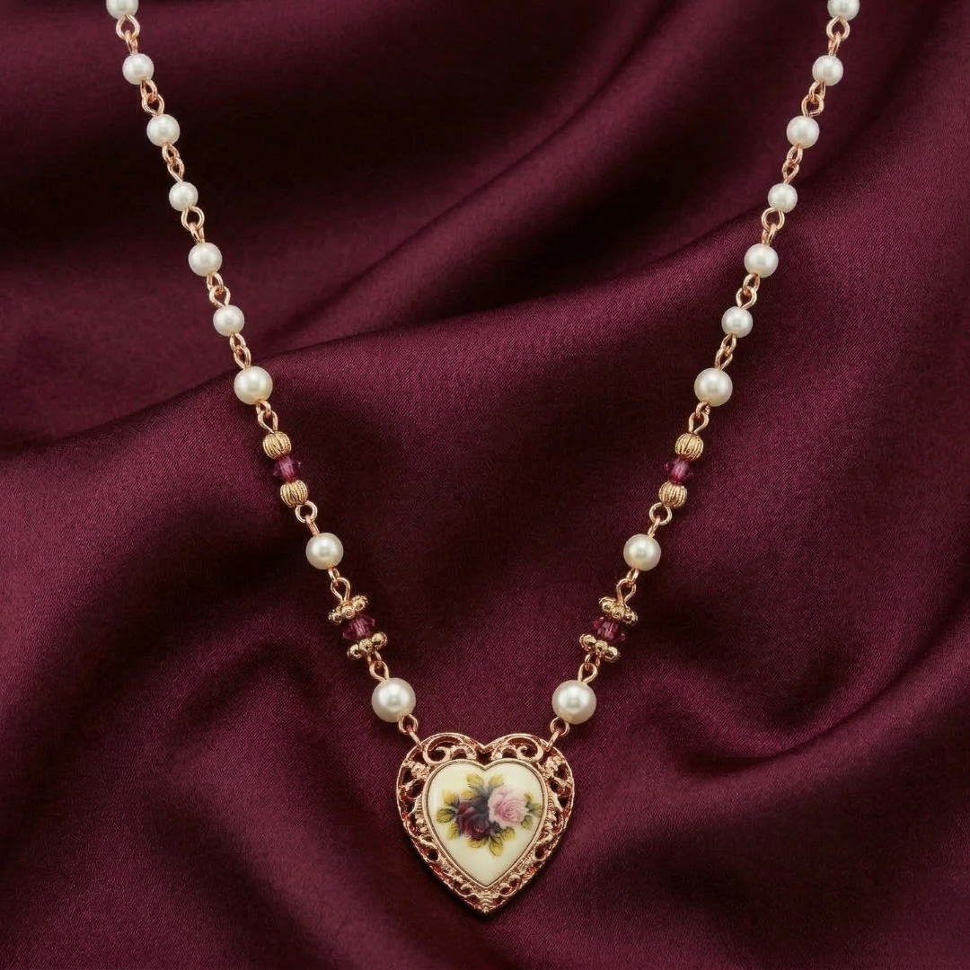 Necklace with heart-shaped pendant and faux pearl beads on a maroon fabric background