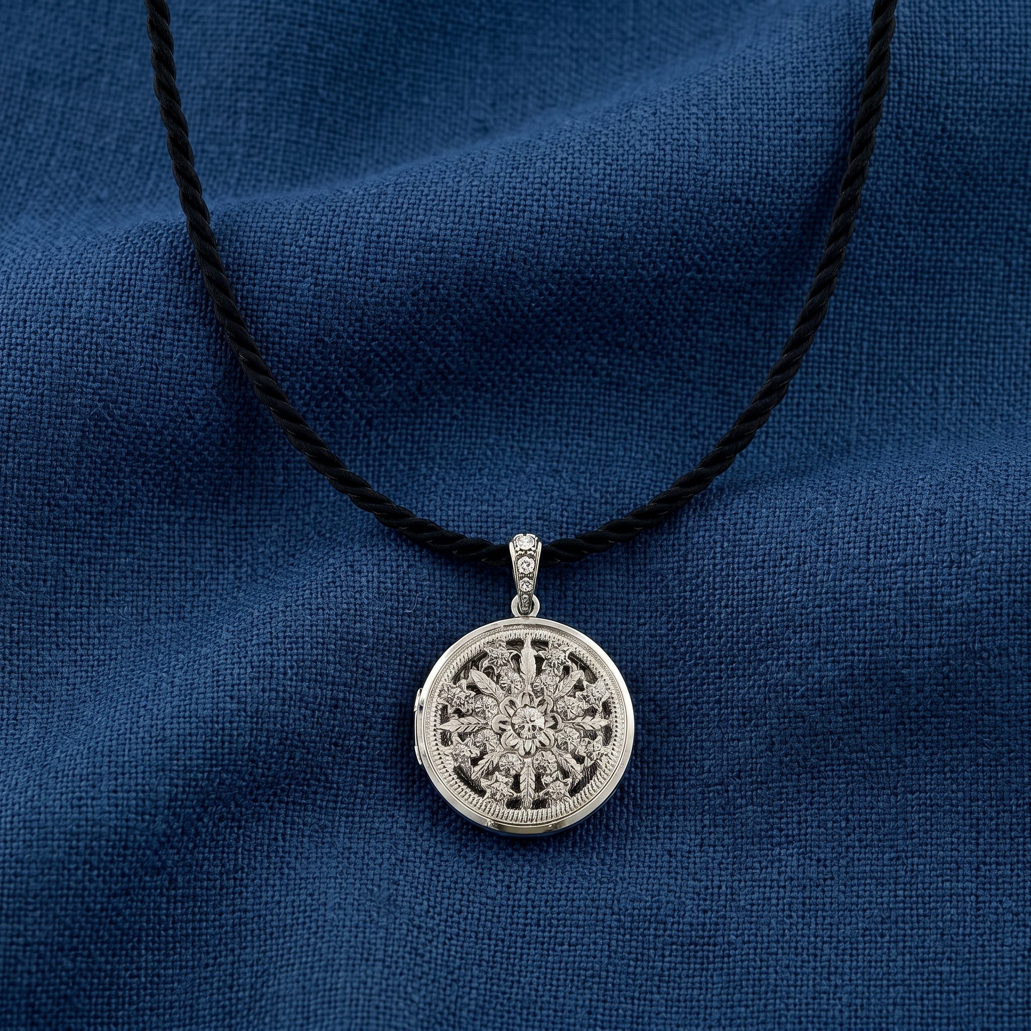 Silver necklace with a round locket pendant on a blue fabric background